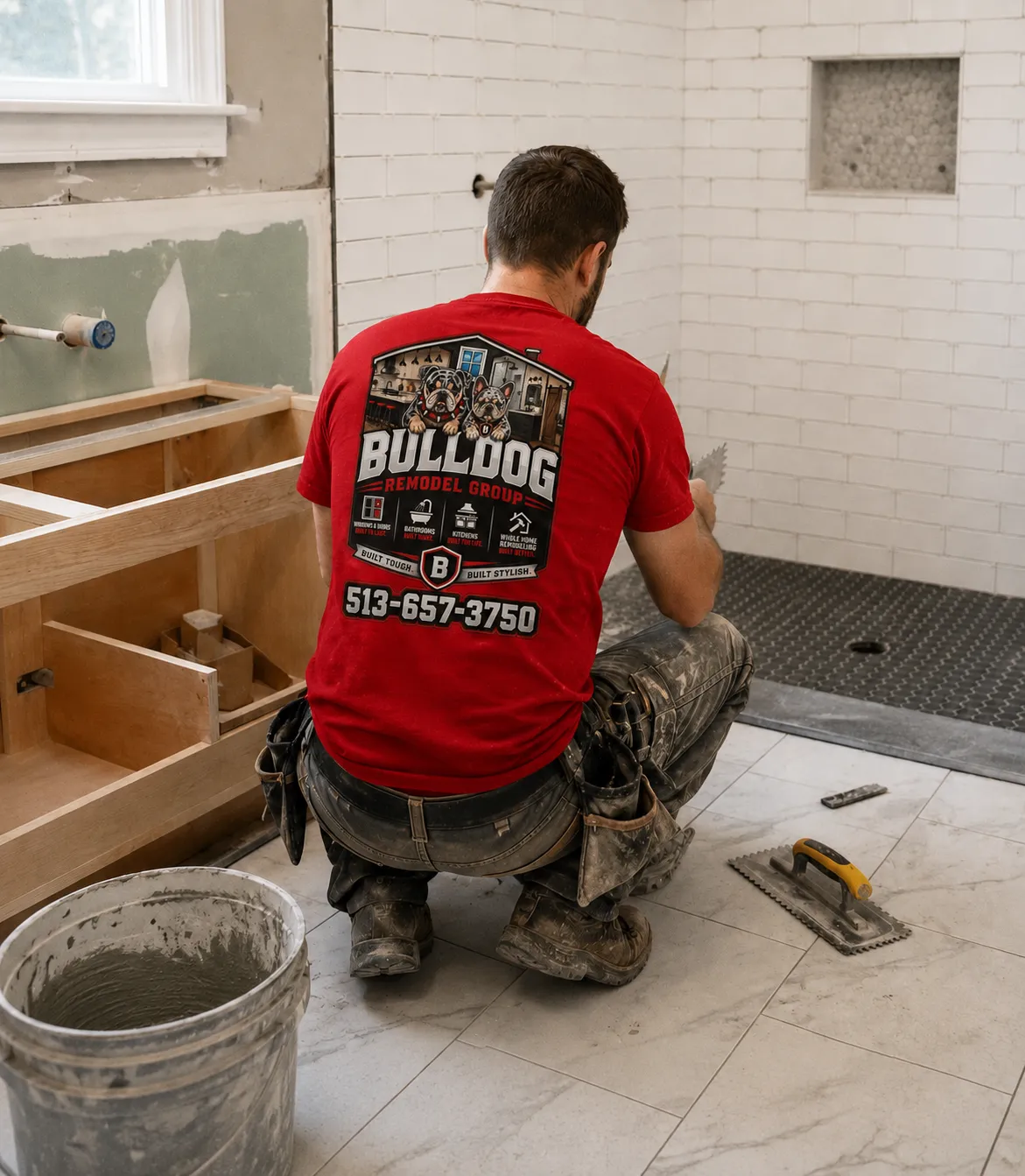 Bulldog Remodel Group tile setter installing floor tile in a subway-tiled bathroom remodel